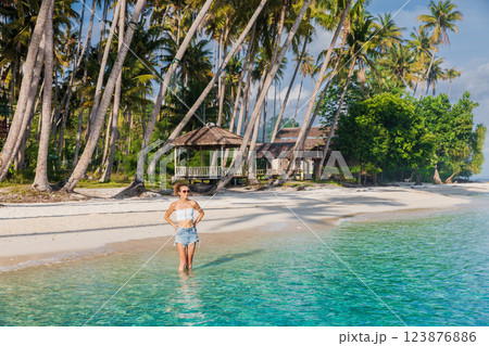 Woman on beach staying in ocean on her vacations. Woman and palm trees Woman on beach staying in ocean on her vacations. Woman and palm trees 123876886