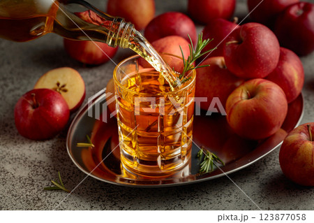 Apple cider is poured from a bottle into a glass. Apple cider is poured from a bottle into a glass. 123877058