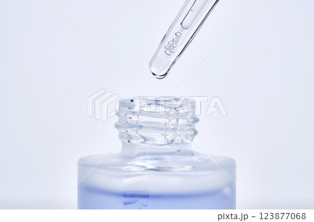 The blue serum drips from the dropper into the bottle. 123877068