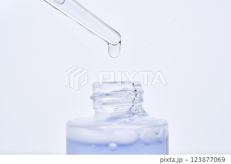 The blue serum drips from the dropper into the bottle. The blue serum drips from the dropper into the bottle. 123877069