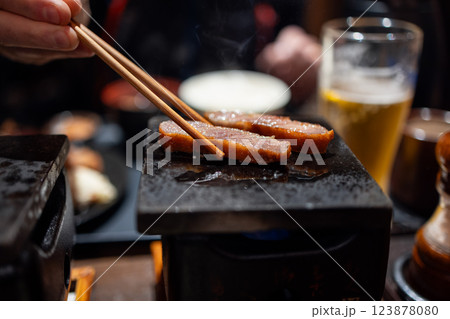 Sizzling gyukatsu beef cutlet searing on a hot stone atop a Japanese tabletop grill 123878080