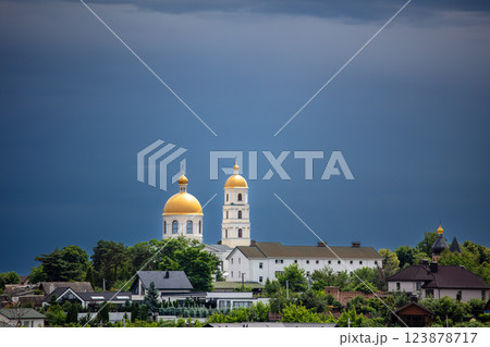 A picturesque town  lush greenery, and golden-domed churches in the background. The dramatic sky adds contrast, creating a serene yet moody atmosphere. 123878717