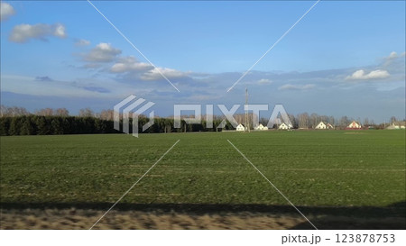 The view from the car window, the car rushing through the countryside. Spring landscape of peaceful rural life on a farm from the window of a speeding car. The view from the car window, the car rushing through the countryside. Spring landscape of peaceful rural life on a farm from the window of a speeding car. 123878753