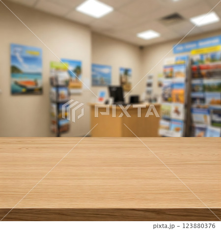 A blurry travel agency interior with brochures and posters, contrasted with a clear wooden tabletop in the foreground 123880376