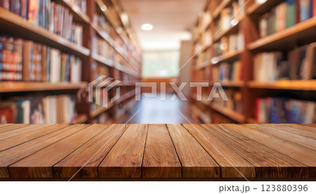 A wooden tabletop with a blurred background of a library aisle filled with bookshelves 123880396