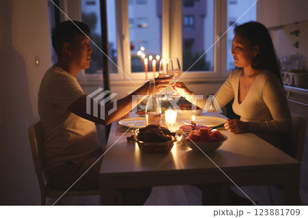 Young couple toasting with wine glasses during romantic candlelit dinner at home Young couple toasting with wine glasses during romantic candlelit dinner at home 123881709