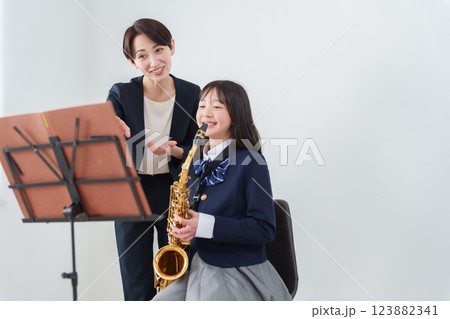 サックスを吹くブラスバンド部員と顧問の女性教師 123882341