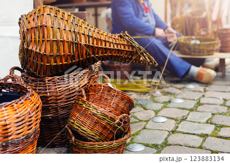 Artisan Dutch person weave natural wicker strips handmade basket sitting street traditional fair Holland festival street. Man make rustic vintage Netherlands craft items. Basketry handicraft workshop 123883134