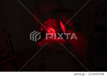 Relaxing skin treatment in a dimly lit room with red lighting Relaxing skin treatment in a dimly lit room with red lighting 123883306