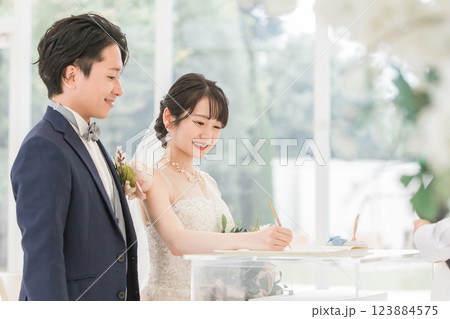 結婚式で結婚証明書・結婚誓約書にサイン・署名をする新郎新婦 結婚式で結婚証明書・結婚誓約書にサイン・署名をする新郎新婦 123884575