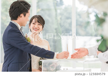 結婚式で結婚証明書・結婚誓約書にサイン・署名をする新郎新婦 123884579