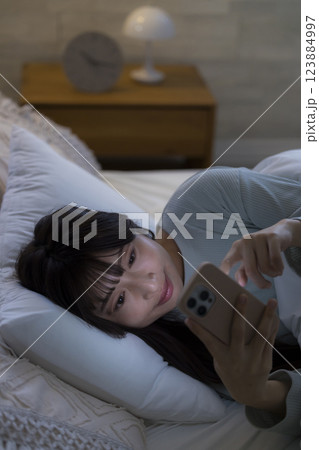ベッドでスマホを見る女性　　 123884997