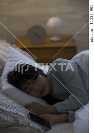 ベッドでスマホを見る女性　　 123884999