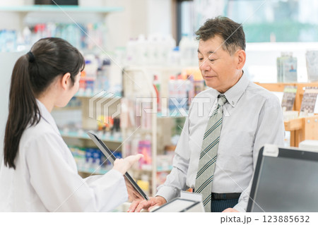 薬局でタブレットPCを使いながら説明を受けるシニア性と女性薬剤師(レセコン・レセプトコンピュータ) 薬局でタブレットPCを使いながら説明を受けるシニア性と女性薬剤師(レセコン・レセプトコンピュータ) 123885632