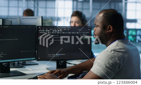 Ill Admin programming in server room housing advanced equipment coming up with flu, feeling sick. Developer suffering from cold, coughing while typing code on PC to mend data center racks, camera A 123886004