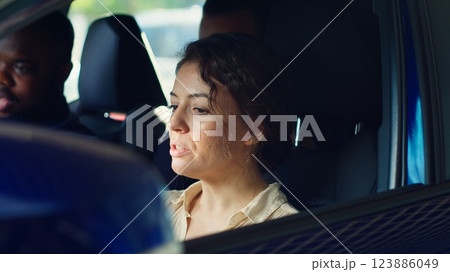 Woman buying car, doing test drive, evaluating if steering wheel feels comfortable, looking out for potential lag. Customers in vehicle with salesman driving to see how automobile reacts, camera A Woman buying car, doing test drive, evaluating if steering wheel feels comfortable, looking out for potential lag. Customers in vehicle with salesman driving to see how automobile reacts, camera A 123886049