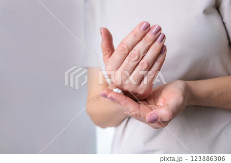 A mature woman of the pensioner age with dry skin smears moisturizing cream on her hands. A mature woman of the pensioner age with dry skin smears moisturizing cream on her hands. 123886306
