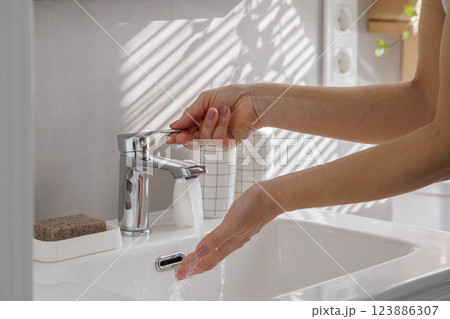 Female hands close up near white clean washbasin with running clean water Female hands close up near white clean washbasin with running clean water 123886307