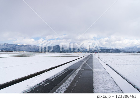 積雪の田園を貫く舗装道路 123886463