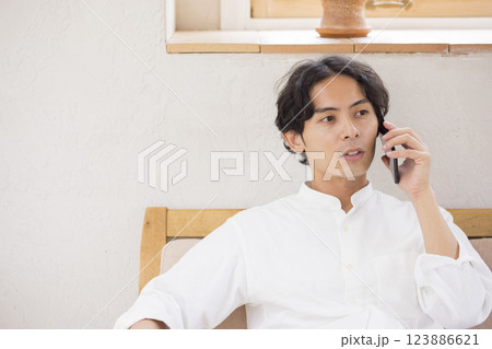 ソファーに座ってスマホで会話をする若い男性 123886621