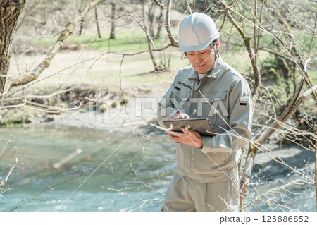 川・河川で河川調査・水質調査をする作業服姿の施工管理技士の男性 123886852