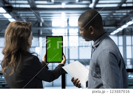 Data center admins using isolated screen tablet to calibrate energy usage. Server hub workers using chroma key device to inspect UPS configurations, doing maintenance on equipment Data center admins using isolated screen tablet to calibrate energy usage. Server hub workers using chroma key device to inspect UPS configurations, doing maintenance on equipment 123887016