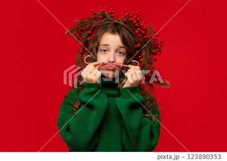 Girl making sad face while holding candy canes as mustache. Girl making sad face while holding candy canes as mustache. 123890353