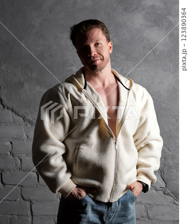 Man in fleece hoodie and jeans, casual pose against wall. Man in fleece hoodie and jeans, casual pose against wall. 123890364