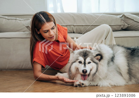 woman is petting a dog on the floor 123891086