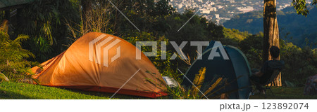 landscape and travel concept with man relax with camping tent on mountain and city background 123892074