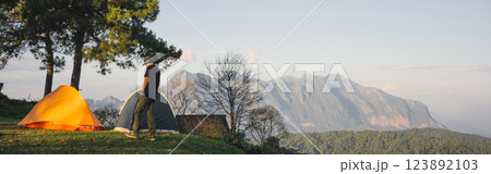landscape and travel concept with asian man relax see sunset camping tent on mountain 123892103