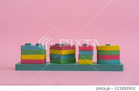 A close-up of a colorful wooden geometric puzzle, designed for Montessori education. The vibrant shapes and natural materials promote learning through play, on a pink background 123892932