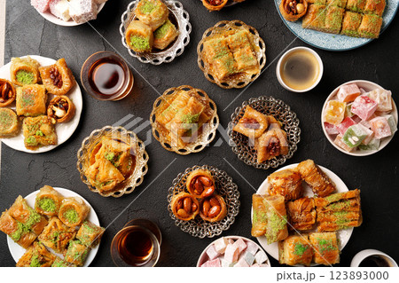 Traditional Middle Eastern sweets served on various plates with drinks in a cozy setting during a festive gathering 123893000