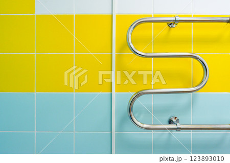 Brightly colored tiled wall with a curved metal handrail in a modern bathroom setting 123893010