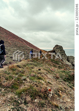 Hikers explore rugged terrain near the coast on an overcast day in a remote location Hikers explore rugged terrain near the coast on an overcast day in a remote location 123893046