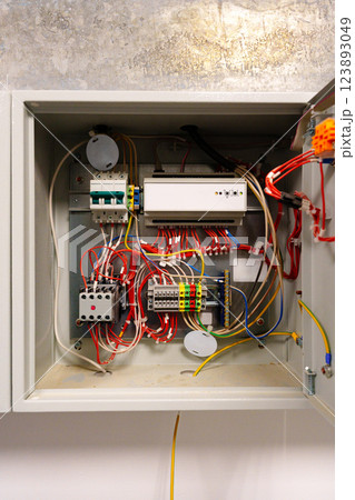 Electrical wiring inside a control box with various connected components in a modern building setting Electrical wiring inside a control box with various connected components in a modern building setting 123893049