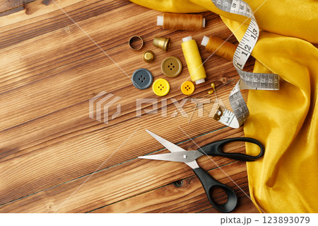 Crafting tools and materials arranged on a wooden table for sewing projects Crafting tools and materials arranged on a wooden table for sewing projects 123893079
