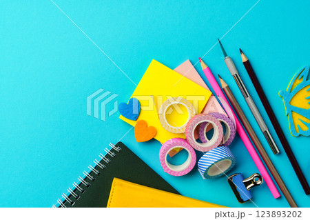 Colorful stationery supplies arranged on a bright blue backdrop for creative projects and crafting activities 123893202
