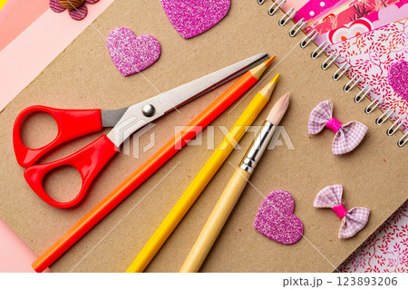Craft supplies arranged on a tabletop featuring scissors, colored pencils, and decorative heart shapes created for a creative project 123893206