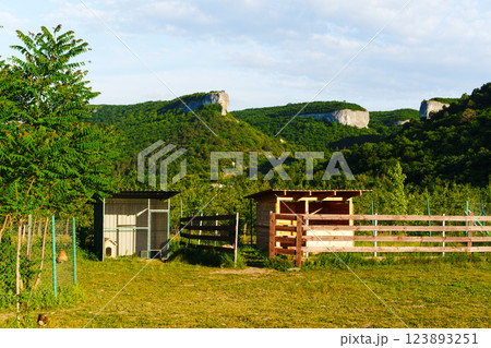 Scenic landscape featuring rustic structures and hills in the background during a sunny day 123893251
