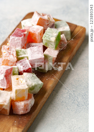 Colorful Turkish delight pieces arranged on a wooden platter with a light background in a kitchen setting Colorful Turkish delight pieces arranged on a wooden platter with a light background in a kitchen setting 123893343