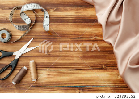 Crafting tools and materials arranged on a wooden table for sewing projects Crafting tools and materials arranged on a wooden table for sewing projects 123893352