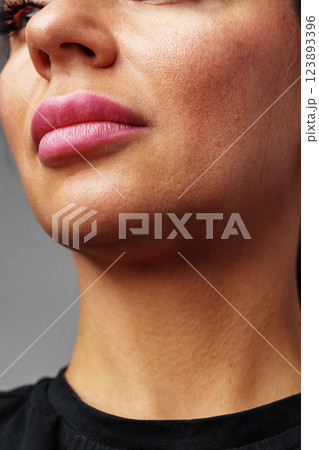 woman showcasing her natural skin texture and subtle lip color in soft lighting 123893396