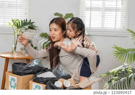 Responsible Parenting and Recycling Education. A mother explains the importance of recycling to her daughter during a sorting session. 123893417