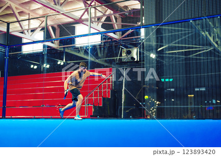 Intense indoor squash player showcases skills during a competitive match in a modern sports facility Intense indoor squash player showcases skills during a competitive match in a modern sports facility 123893420