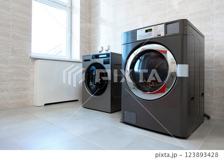 Modern laundry room featuring stylish washing machine and dryer in a bright space with ample natural light Modern laundry room featuring stylish washing machine and dryer in a bright space with ample natural light 123893428