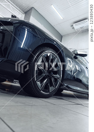 Sleek black car with stylish wheels showcased in modern indoor space during bright daylight 123893430