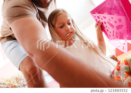 A young girl is looking at a pink stencil, her father is behind her 123893552