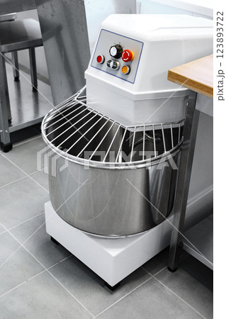 Industrial dough mixer in a modern kitchen setting with a stainless steel bowl and control panel 123893722