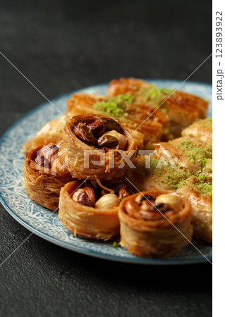 Traditional Middle Eastern sweets arranged on a decorative plate with nuts and syrup at a cultural gathering 123893922